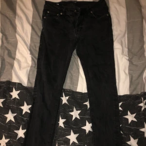 Svarta jeansbyxor skinny  - Snygga svarta jeansbyxor med en klassisk design. De har en rak passform och är perfekta för en stilren look. Byxorna har knappar och dragkedja framtill.