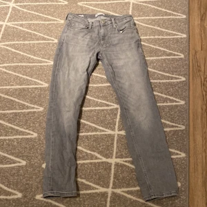 Grå jeans från Jack & Jones - Snygga grå jeans från Jack & Jones i modellen Clark. De har en klassisk femficksdesign och normal passform. Perfekta för en avslappnad stil.