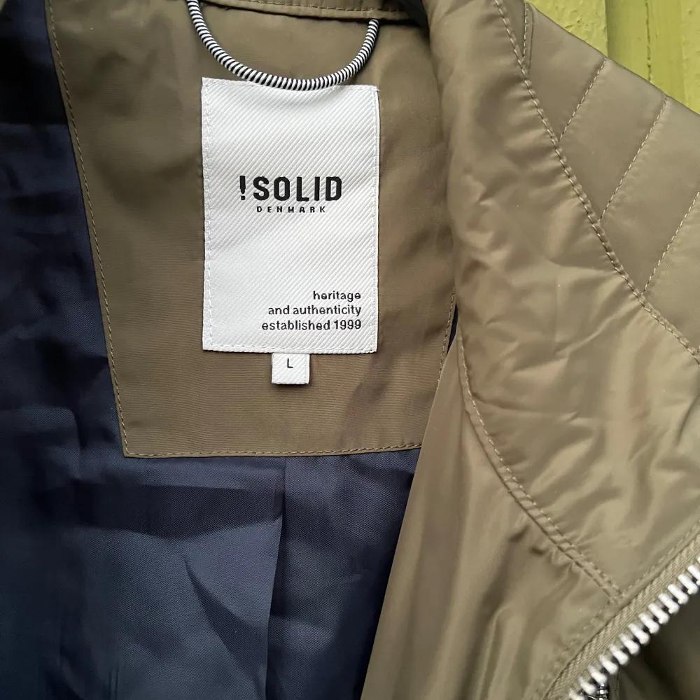 Snygg olivgrön jacka från Solid med dragkedjor och quiltade detaljer på axlarna. Jackan har flera praktiska fickor med dragkedja och en stilren design som passar perfekt för höst och vår.. Takit.