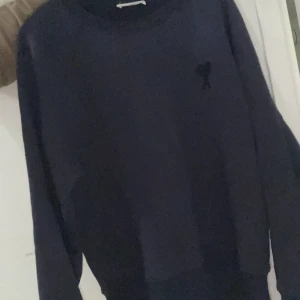 Mörkblå tröja med broderad detalj - Snygg mörkblå tröja med en diskret broderad detalj på bröstet. Perfekt för en stilren och avslappnad look. Tröjan har långa ärmar och en rund halsringning.