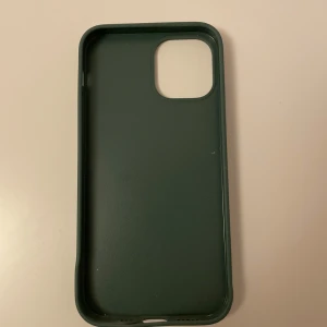 Holdit mobilskal iPhone 12 - Holdit mobilskal i mörkgrön färg för iPhone 12. Lite böjd ner till (se bild), men fungerar lika bra att använda ändå. Annars i gott skick.