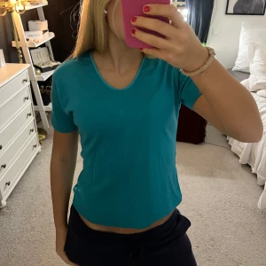 Turkos t-shirt från Abstract - Säljer en turkos t-shirt från Abstract i storlek M. T-shirten har en v-ringad hals och korta ärmar, perfekt för en avslappnad stil.