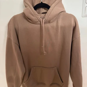 Beige hoodie - Säljer en stilren beige hoodie med känguruficka och justerbar huva. Perfekt för en avslappnad look. Passar bra till både jeans och mjukisbyxor.