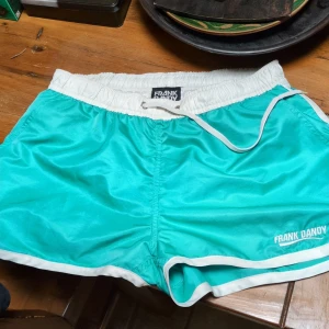 80-tal stil Badbyxor / shorts från Frank Dandy - Snygga shorts från Frank Dandy med vit resårmidja och snörning. Perfekta för sommarens alla äventyr! 🏖️
