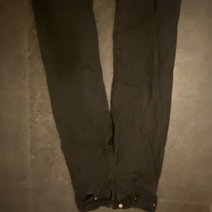 Svarta byxor med knappar - Snygga svarta byxor med knappar vid bensluten. Perfekta för en stilren look och passar till många olika tillfällen.