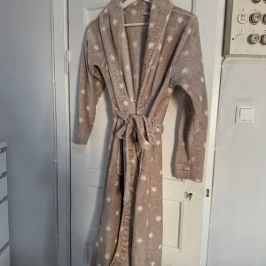 Morgonrock 🤎🤍 - Beige/Ljusbrun morgonrock med vita stjärnor på som köptes på Sellpy i som enligt dom var i ”Mycket bra” skick, men jag skulle säga att den är i ”Bra” skick. Den är använd en gång men tycker att den är lite för kort i ärmarna och lite liten i storleken. Storlek M men känns mer som en S. Den har 2st snören som man kan justera beroende på hur tajt den ska sitta och dom har små trådar som sticker ut. FÖRST TILL KVARN!