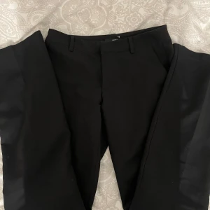 Svarta kostymbyxor från BikBok - Snygga svarta kostymbyxor från BikBok i storlek 36. De har en klassisk design med lowwaist passform, bootcut och perfekta för en stilren look.