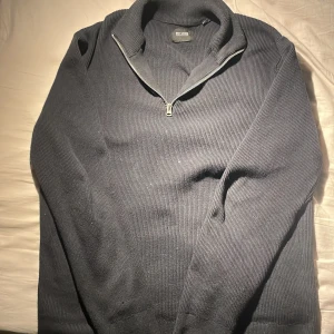 Mörkblå tröja med dragkedja från Only & Sons - Säljer en stilren mörkblå tröja från Only & Sons. Tröjan har en dragkedja vid halsen och är ribbad för en snygg look. Perfekt för kyligare dagar. L men sitter mer som något mellan M och L