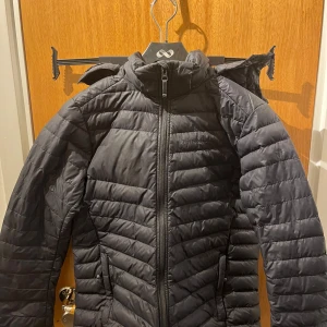 Svart dunjacka från Peak Performance - Säljer en svart dunjacka från Peak Performance. Jackan har en quiltad design med dragkedja framtill och en hög krage. Perfekt för kyligare dagar med sin varma och bekväma passform . Finns ett fåtal små märken på den men dem syns knappt.  Modellen heter : Style JR FROST DH