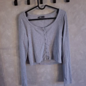 Grå ribbad kofta från FB Sister - Säljer en stilren grå ribbad kofta från FB Sister. Den har långa ärmar och knappar framtill, perfekt för en avslappnad look. Koftan är croppad och passar bra till både jeans och kjol.