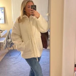 Vit teddyjacka med dragkedja - Mysig vit teddyjacka med dragkedja och fickor. Jackan har en lite oversized passform. Väldigt lik den populära teddyjackan från HM😍använd fåtal gånger, den är som ny!