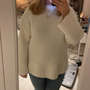Vit fluffig tröja - Mysig vit tröja med lång ärm och fluffig textur. Perfekt för kyliga dagar när du vill känna dig bekväm och stilren. Tröjan har en enkel design som gör den lätt att matcha med olika outfits.