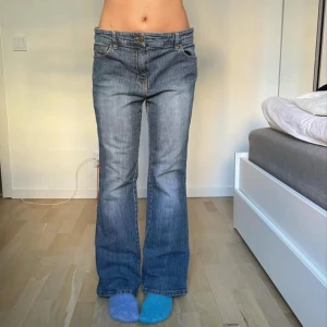 Blå bootcut jeans - Snygga blå bootcut jeans med låg midja. Perfekta för en avslappnad stil. Klassisk design med fem fickor och knappgylf.