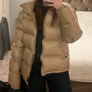 Beige dunjacka från JOTT - Säljer en snygg beige dunjacka från JOTT. Jackan har en dragkedja framtill och är perfekt för kyligare väder. Den är långärmad och har en pufferdesign som ger en trendig look. Perfekt för höst och vinter! I princip helt oanvänd. Liten i storleken! Jag är 168 cm och vanligtvis bär storlek S/M. Nypris: 3300. Pris kan diskuteras:)