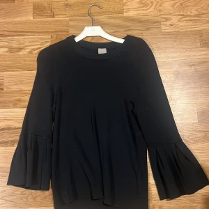   tröja från H&M - Säljer en stilren tröja från H&M i storlek XS. Tröjan har långa ärmar med volangdetaljer vid ärmsluten och en rund halsringning. Perfekt för en chic och enkel look. Mörk grå, grön nästan svart färg men lite ljusare 
