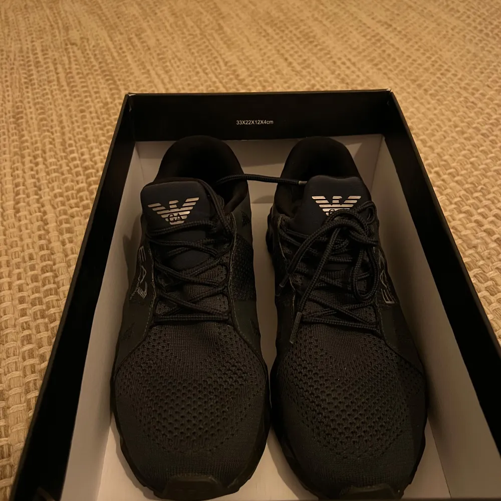 Snygga svarta sneakers från Emporio Armani med en unik geometrisk sula och diskret logga på sidan. Skorna har snörning och är perfekta för träning eller vardagsbruk. Storlek 38 2/3. Knappt använda. . Kengät.