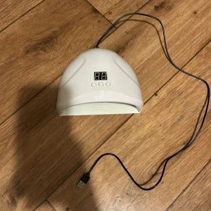 Vit UV LED nagellampa - Säljer en vit UV LED nagellampa med digital display och tre knappar för tidsinställning. Lampan har en USB-kabel för enkel anslutning. Perfekt för att härda gelnagellack hemma.