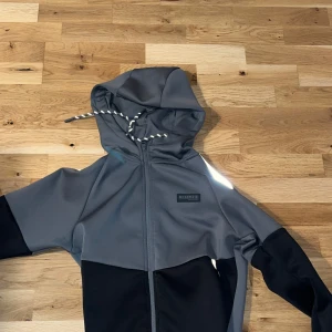 Grå och svart hoodie från McKenzie - Snygg grå och svart hoodie från McKenzie med dragkedja och justerbar huva. Perfekt för en avslappnad stil. Tillverkad i mjukt material för extra komfort.