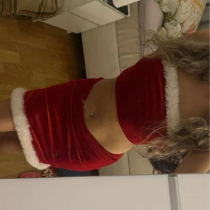 Röd sammetskjol med vit kant - Snygg röd sammetskjol med vit fluffig kant. Perfekt för en festlig look. Kjolen är kort och har en tight passform.