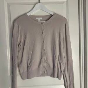 Beige kofta från H&M - Säljer en stilren beige/rosa kofta från H&M i storlek S. Koftan har långa ärmar och knappar framtill, perfekt för lager-på-lager under kyligare dagar. Enkel och klassisk design som passar till det mesta.