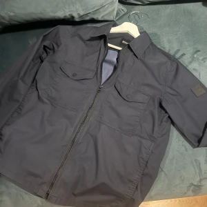 Hugo Boss overshirt - Snygg navy blue overshirt ifrån hugo boss. Lite vind/regn jacka material. Storlek s. Ny pris ligger på 1300kr