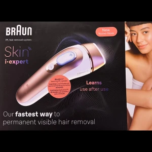 Braun Smart IPL Skin i-expert PL7147 - Oanvänd! Braun Skin i-expert är ett IPL hårborttagningssystem som erbjuder permanent synlig hårborttagning. Den har en elegant design med en rosa och vit färgkombination. Enheten lär sig och anpassar sig efter användning för effektivare resultat. 