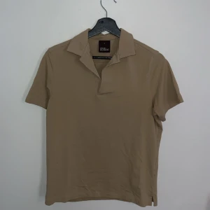 Oscar Jacobson piké - Super fin och fräsch piké från Oscar Jacobson, använd endast en gång då den tyvärr är för liten. Så tröjan är helt som ny. Färgen är lite svår att få på bild men den är mer beige än brun.