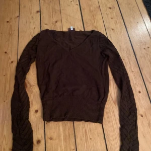 Fin långärmad brun tröja med coola stickade detaljer på ärmarna - Cool tröja med fina stickade ärmar, bra skick köpt second hand med några trådar i slutet av ärmen!