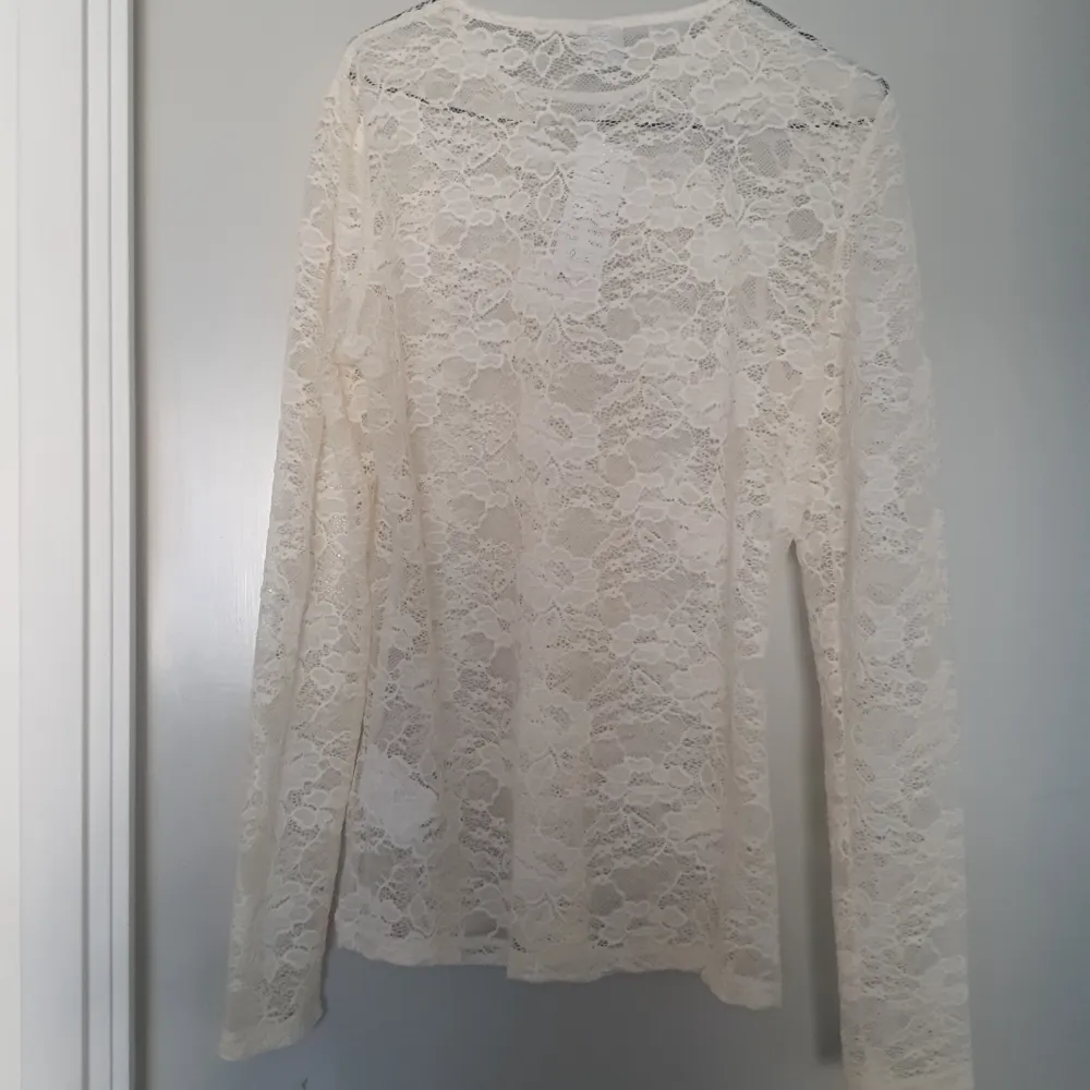 Säljer en superfin vit spetsblus med långärmad design. Perfekt för både vardag och fest! Blusen är genomskinlig och har ett elegant mönster som ger en romantisk touch. Passar perfekt till ett par jeans eller en kjol för en chic look. Ny PRISLAPP kvar. Yläosat.