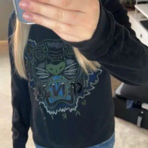 Svart tröja från Kenzo med tigertryck - Säljer en svart tröja från Kenzo med ett coolt tigertryck på framsidan. Använd fåtal gånger, jättebra skick💕