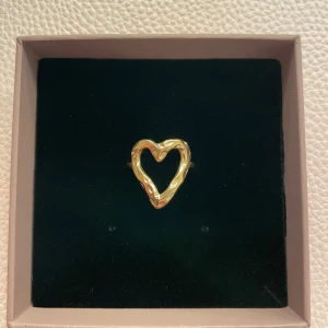Guld ring hjärta - Säljer en fin ring i form av ett hjärta. Det har en unik, vågig design. Perfekt för att ge en fin känsla till din outfit. Passar både till vardags och festliga tillfällen. Helt ny och justerbar! (Låda tillhör inte)