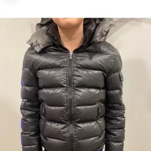 Säljer en snygg svart pufferjacka från Moncler i mycket bra skick. Jackan har en dragkedja framtill och en mysig huva. Perfekt för kalla vinterdagar med sin varma och quiltade design. Den är långärmad och har en stilren look som passar både till vardags och fest.