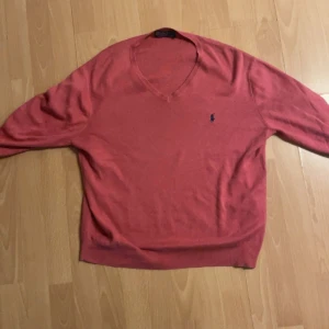 Rosa tröja från Polo Ralph Lauren - Säljer en snygg rosa tröja från Polo Ralph Lauren i storlek L. Den har en klassisk v-ringning och är perfekt för både vardag och fest. Tröjan är i bra skick och har långa ärmar. Perfekt för höst och vår!