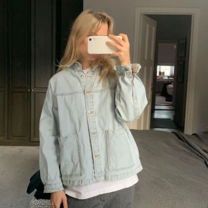 Ljusblå jeansjacka - Säljer en snygg ljusblå jeansjacka i bra skick. Jackan har en avslappnad passform med stora fickor fram och knappar hela vägen. Perfekt för vår och sommar!  