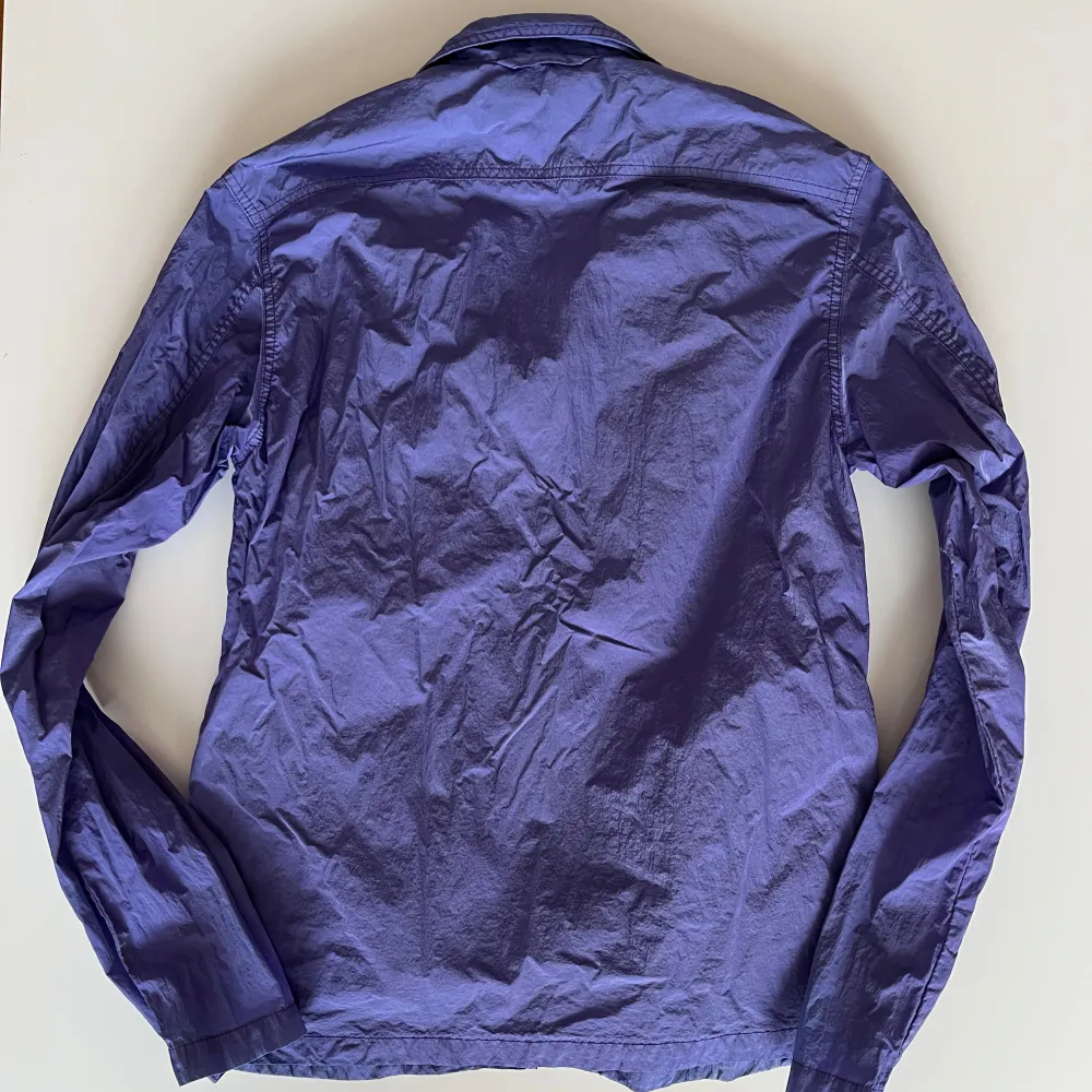 Säljer en snygg lila vindjacka i mycket bra skick. Jackan har en dragkedja framtill och långa ärmar, fickor i sidorna. Perfekt för vår och höst när det blåser lite extra. Den är i nylon likt stone island jackor!. Takit.