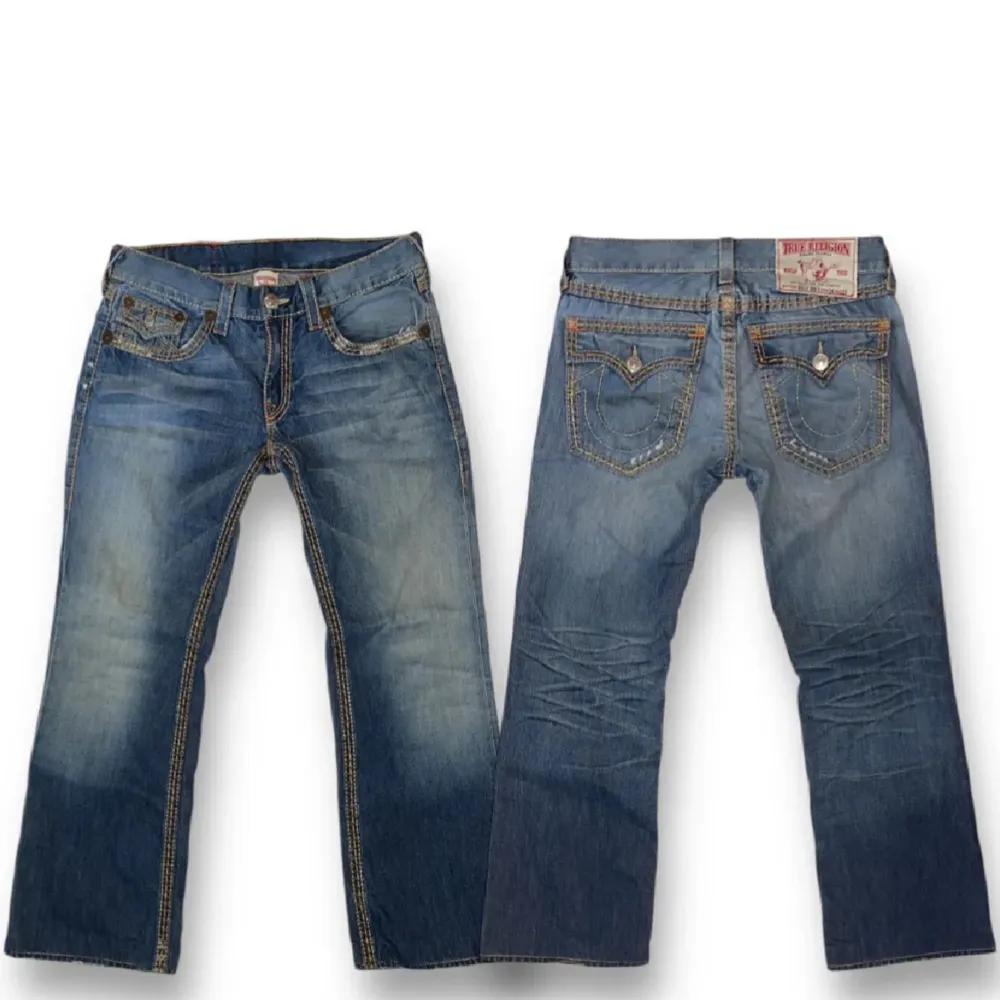 Säljer ett par snygga blå jeans från True Religion. De har en klassisk femficksdesign med coola kontrastsömmar och en unik bakficka med knapp. Perfekta för en avslappnad stil med en touch av lyx. Passar både till vardags och fest!. Jeans & Byxor.