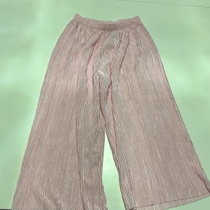 Rosa plisserade byxor - Säljer ett par supercharmiga rosa plisserade byxor. De har en loose passform och är perfekta för både vardag och fest. Materialet är lätt och luftigt, vilket gör dem sköna att bära. Perfekta för vår och sommar! 🌸