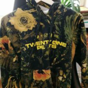 Mönstrad hoodie från Twenty One Pilots - Säljer en cool hoodie från Twenty One Pilots med ett unikt blommönster i gult och grönt. Den har en bekväm passform och är perfekt för höst och vår. Hoddien är från trench turen och kan endast köpas second hand nu för tiden.