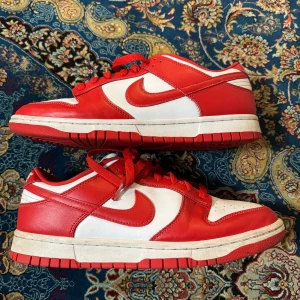 Nike Dunks low  - Jag säljer ett par röda, vita nike dunks då jag har bytt stil. Skorna är i bra skick. 