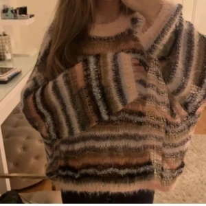 Randig fluffig tröja  - Supermysig och fluffig tröja med randigt mönster i rosa, svart och beige. Perfekt för kyliga dagar när du vill vara både varm och stilren. Tröjan har en loose passform och långa ärmar, vilket gör den extra bekväm. Passar perfekt till höst och vinter och supersnyggt att ha något under!