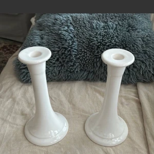 Vita ljusstakar från Guldkroken - Säljer ett par eleganta vita ljusstakar från Guldkroken. De har en stilren och tidlös design, perfekt för att ge ditt hem en klassisk touch. Ljusstakarna är i keramik och har en glansig yta. De är i fint skick med några små märken undertill. Perfekta för både vardag och fest! 🕯️