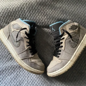 Jordan 1 - Säljer ett par grå Nike Air sneakers i bra skick. De har snygga blå detaljer och svart snörning. Perfekta för vardagsbruk eller träning. Skorna har en cool design med det klassiska Nike-märket på sidan.