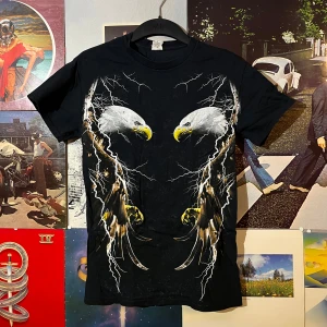 Vintage tshirt  - Snygg vintage t-shirt från Gildan med ett mäktigt örnmotiv och blixtar på framsidan. Perfekt för dig som vill sticka ut med en unik stil. Gjord i kraftig bomull för en skön känsla. Passar perfekt till vardags eller en avslappnad festkväll.