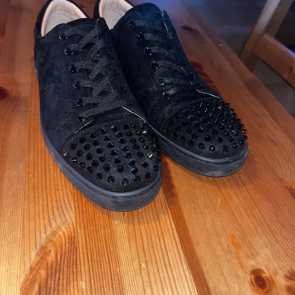 Säljer ett par svarta sneakers från Christian Louboutin i mycket bra skick. Skorna är i mocha och har nitar på tån. De har den klassiska röda sulan och snörning framtill. Perfekta för en fest eller en utekväll!. Skor.