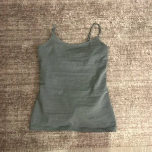Grå linnetopp - Säljer en stilren grå linnetopp med smala axelband. Perfekt för sommardagar eller som ett basplagg under andra kläder. Toppen har en tight passform och är i mycket bra skick. Superbekväm och lätt att matcha med olika outfits! Man kan inte se storleken men det är s-xs