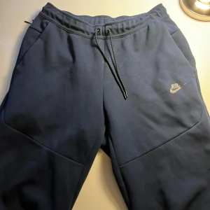 nike tech - Säljer ett par blåa nike tech byxor som är i bra skick och i storlek M