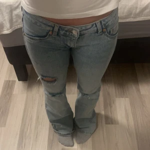 Ljusblå jeans med slitningar - Säljer ett par ljusblå jeans i storlek EUR 38. De har en snygg slitning och är i en bootcut-stil. Perfekta för er som gillar lågmidjade jeans. Säljer då de inte kommer till användning lika mycket länge. Jag är 165 cm ungefär och de passar mig i längden. 
