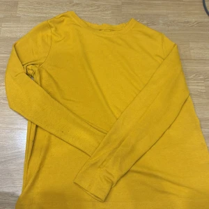 Gul långärmad tröja - Säljer en snygg gul långärmad tröja i bra skick. Perfekt för höst och vår, med en härlig färg som lyser upp vilken dag som helst. Tröjan är mjuk och bekväm, idealisk för vardagsbruk eller en avslappnad dag ute. Passar perfekt till jeans eller kjol!