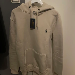 Polo Ralph Lauren Beige  - Säljer en snygg beige hoodie från Polo Ralph Lauren. Den är helt ny! Jättebra skick, har tyvärr ej kvitto då det var en present. Hör gärna av er vid fler frågor!