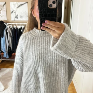 Grå stickad tröja - Mysig grå stickad tröja i oversized passform. Den har långa ärmar och en ribbad struktur som ger en stilren look. 